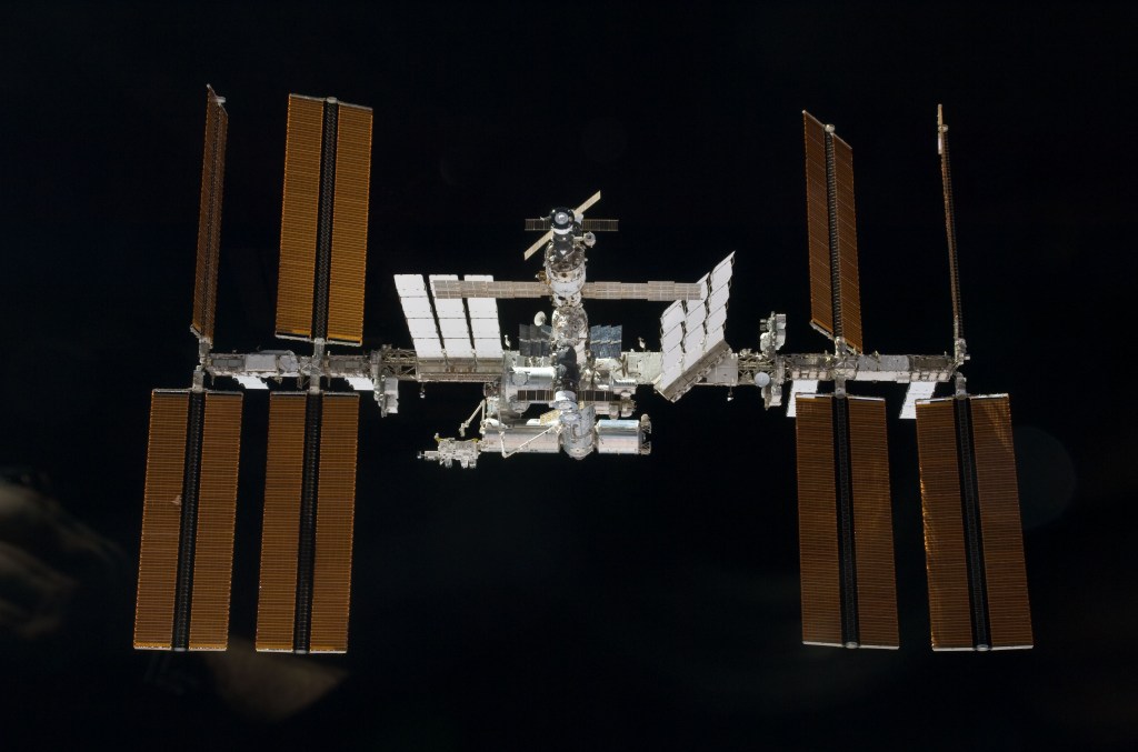 View of the International Space Station as seen from a departing space shuttle, against the blackness of space.