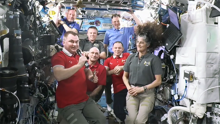 Cosmonaut Alexey Ovchinin (left) speaks to mission controllers after astronaut Suni Williams (right) handed over command of the International Space Station to the veteran crew member as the rest of the Expedition 72 crew looks on.