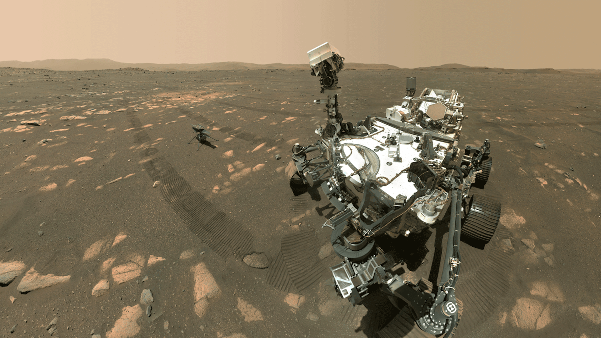 The Perseverance rover and the Ingenuity helicopter on the Martian surface, with the rover's camera moving to look down at Ingenuity.