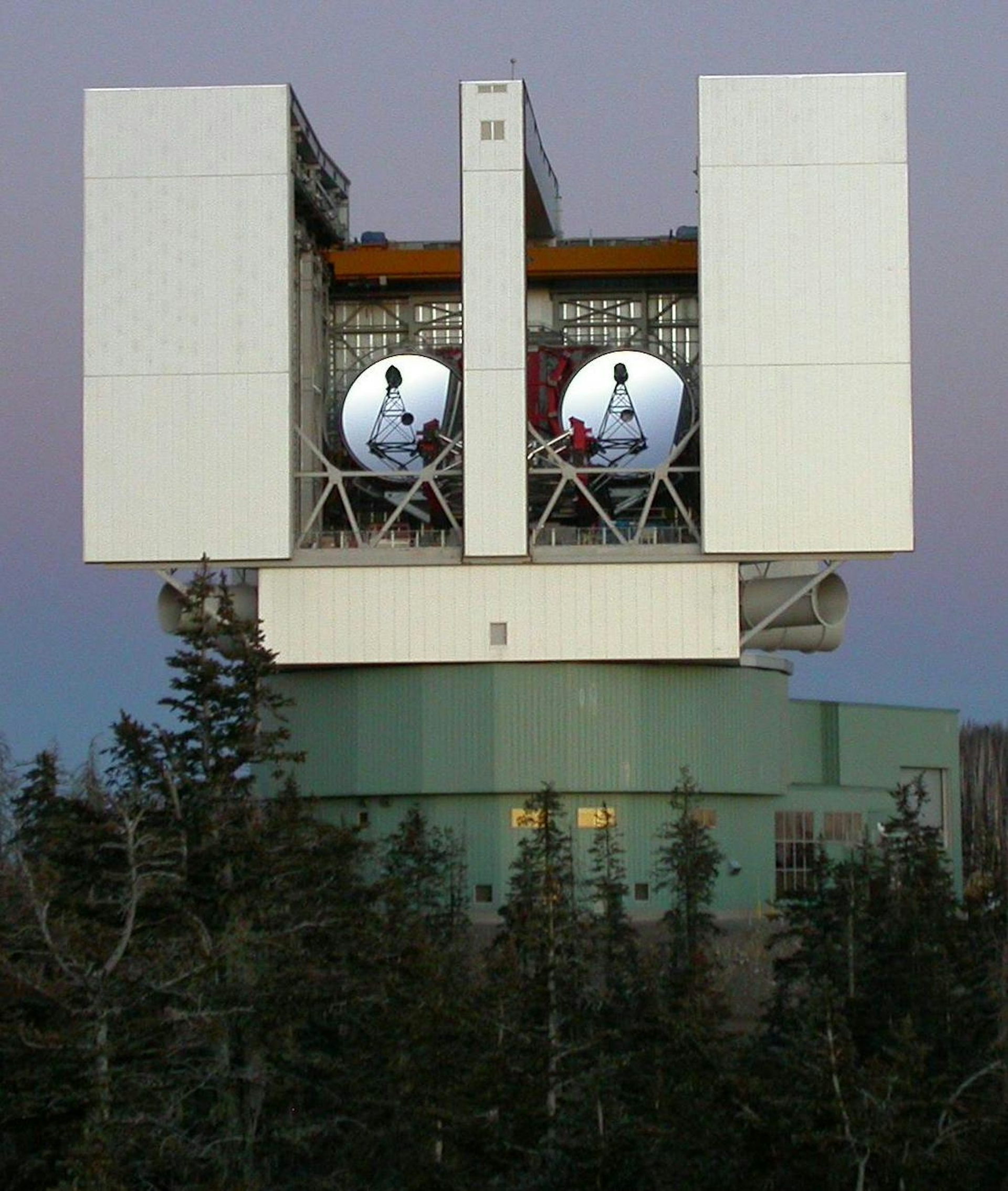 A telescope on a mountaintop set in a box with two antenna disks