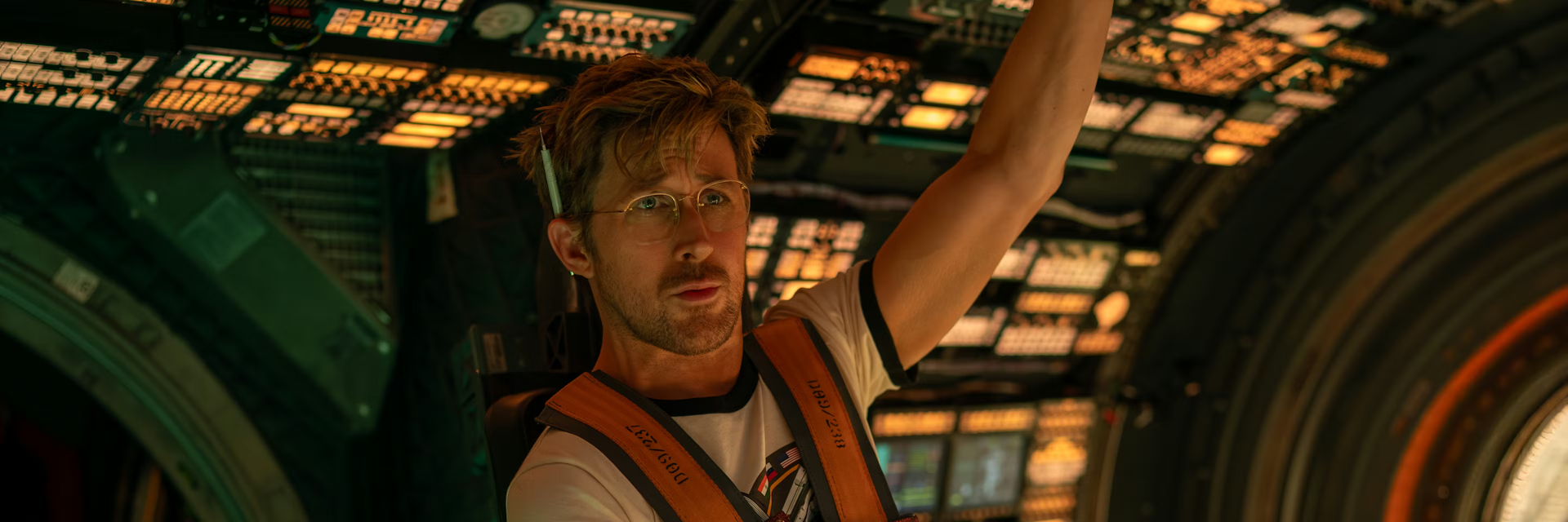 Ryan Gosling dressed as Ryland Grace, strapped into the pilot's chair of a spaceship.