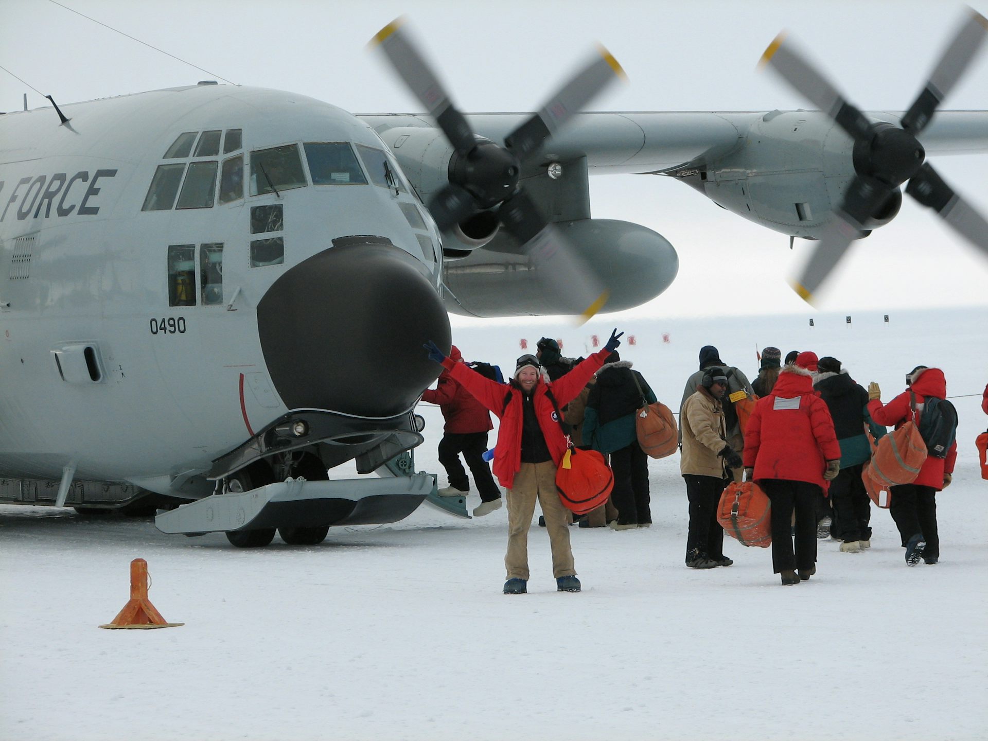 People in winter gear cluster around an airplane on snowy ground.